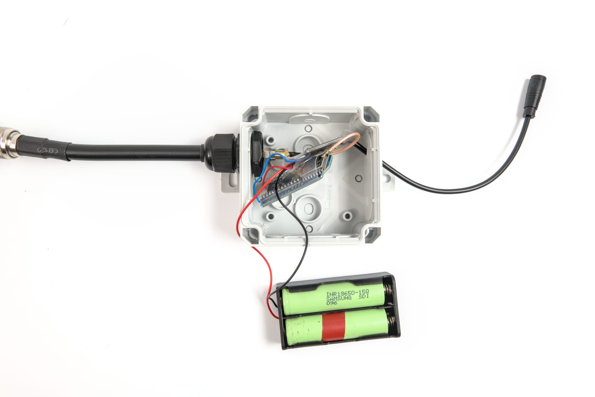 Interior of an IP68 junction box containing a Meshtastic node with 18650 batteries and TP4056 charge controller.