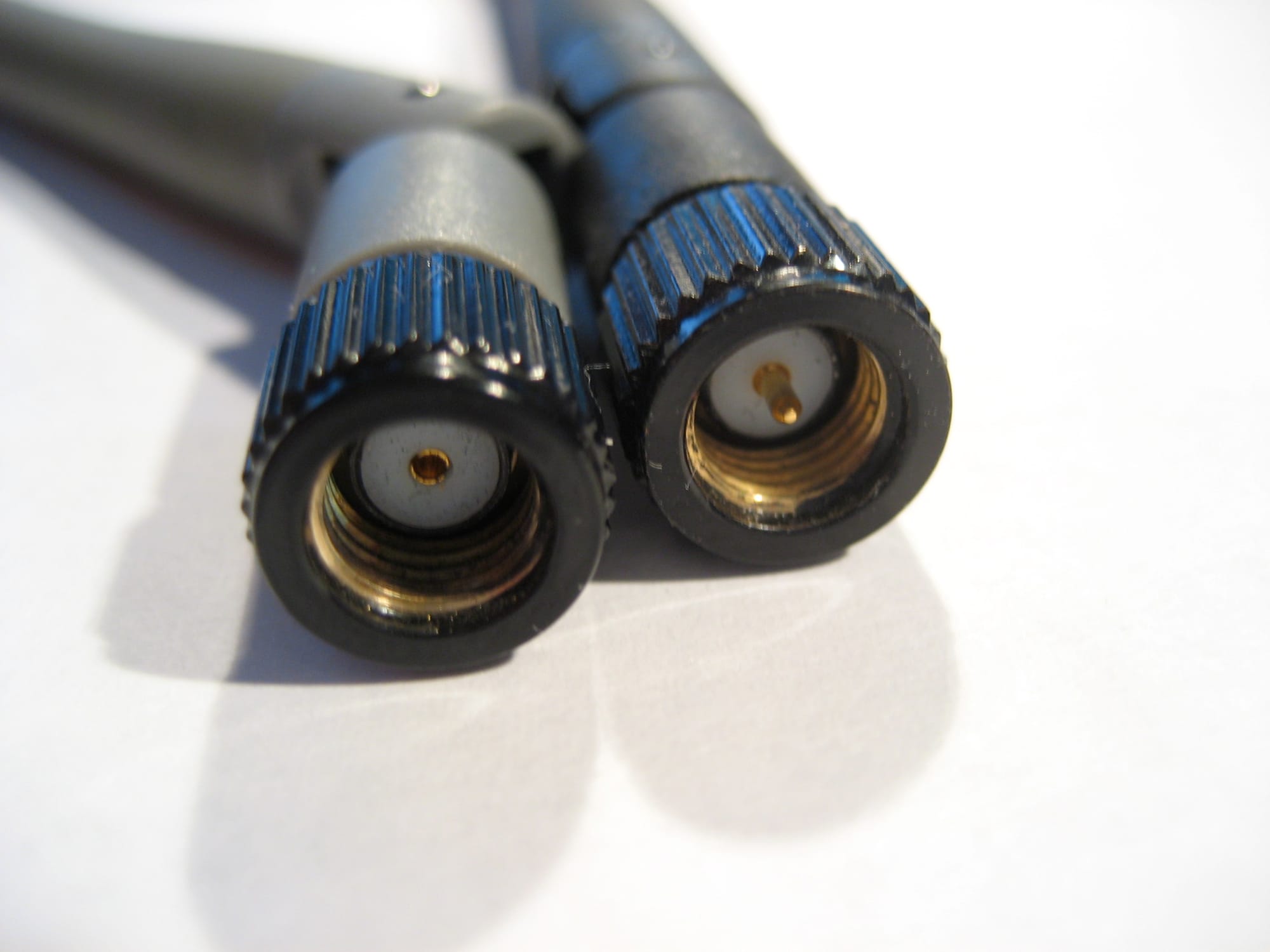RP-SMA plug on the left and SMA plug on the right, showing the center conductor difference, socket vs pin.