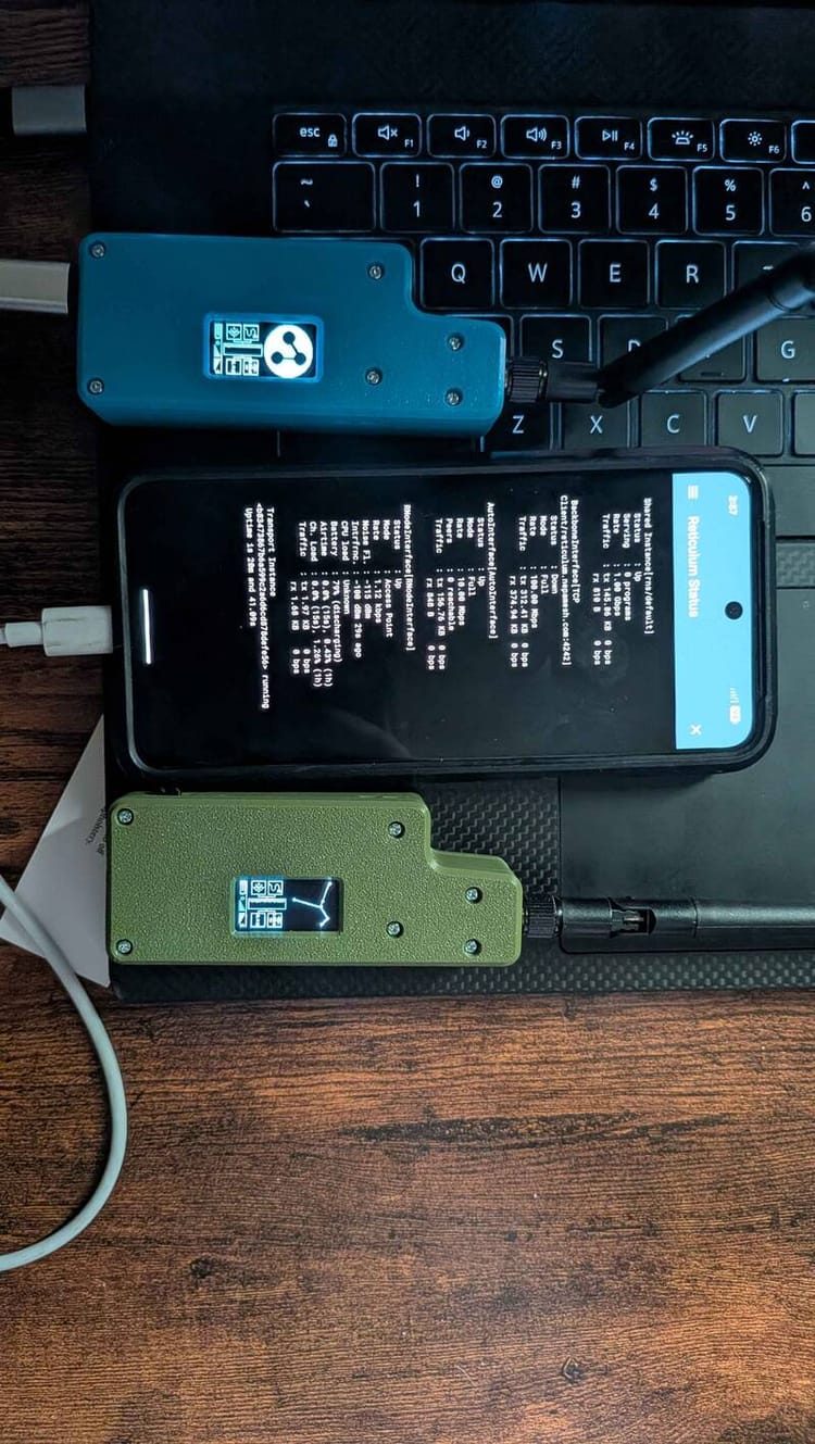 Two RNode LoRa radios next to a phone showing live Reticulum status output, all resting on a laptop keyboard