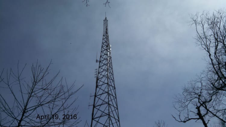 A self-supporting amateur radio tower with antennas mounted on a mountain ridge at over 4,000 feet elevation, similar to the ridge-top router sites NEPAMesh depends on for coverage.