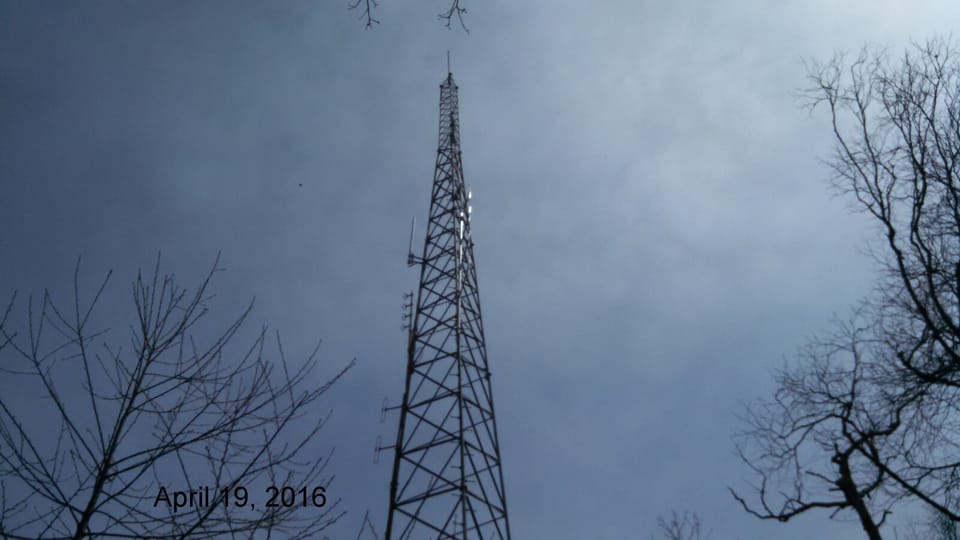 A self-supporting amateur radio tower with antennas mounted on a mountain ridge at over 4,000 feet elevation, similar to the ridge-top router sites NEPAMesh depends on for coverage.